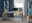 Moderner E-Schreibtisch in einem stilvollen Büro mit Blick auf die Natur durch ein großes Fenster. Der Schreibtisch ist aus Holz mit Metallbeinen und bietet Platz für einen Computer und Schreibtischzubehör. Perspektive: Frontalansicht.