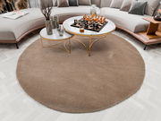 Runder, beiger Teppich mit einem Durchmesser von ca. 200 cm in einem modernen Wohnzimmer, von oben betrachtet. Der Teppich liegt unter einem eleganten Couchtisch mit Marmorplatte und goldenen Beinen, umgeben von einem geschwungenen Sofa.