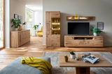 Wohnzimmer mit moderner Holzmöbelkombination, bestehend aus Sideboard, Vitrine und TV-Board, aus der Perspektive des Sofas betrachtet.