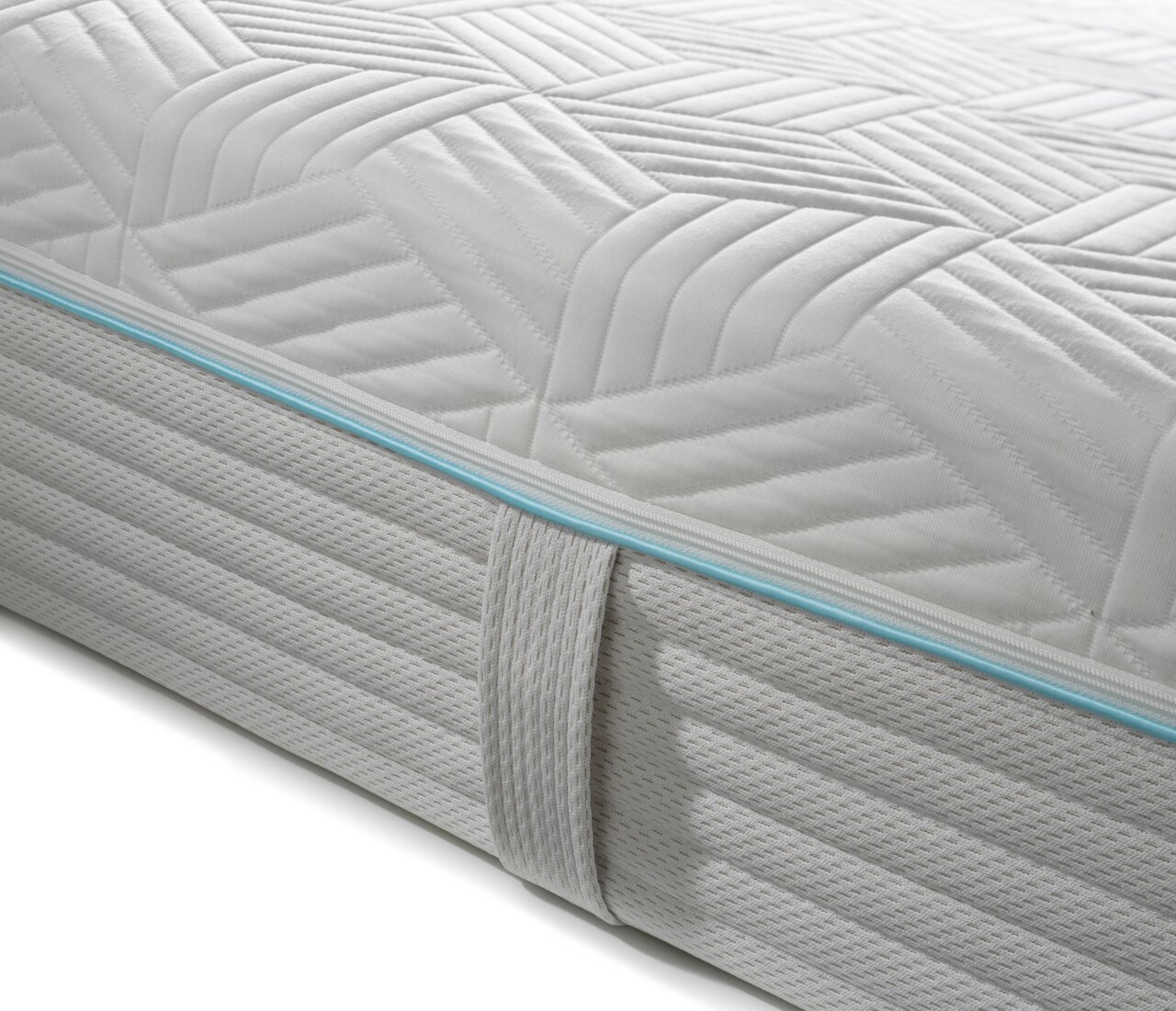 Nahaufnahme einer Gel-Kaltschaummatratze mit gestepptem Muster und blauer Zierleiste, seitliche Perspektive