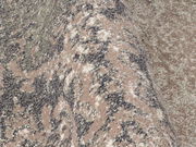 Nahaufnahme eines Designer Teppichs mit abstraktem Muster in Erdtönen, aus seitlicher Perspektive aufgenommen.