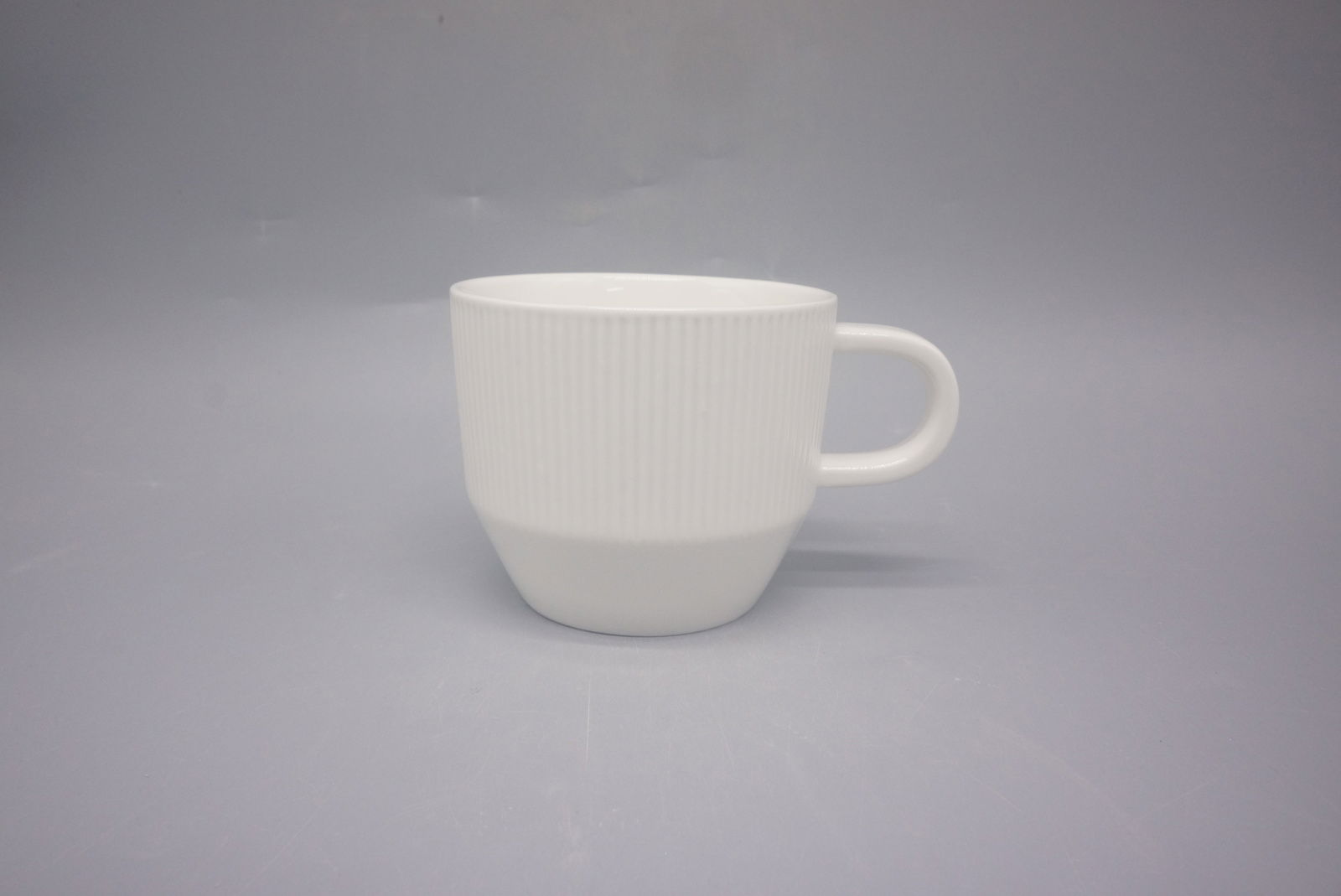 Weiße Kaffeetasse mit geriffelter Oberfläche, seitliche Perspektive