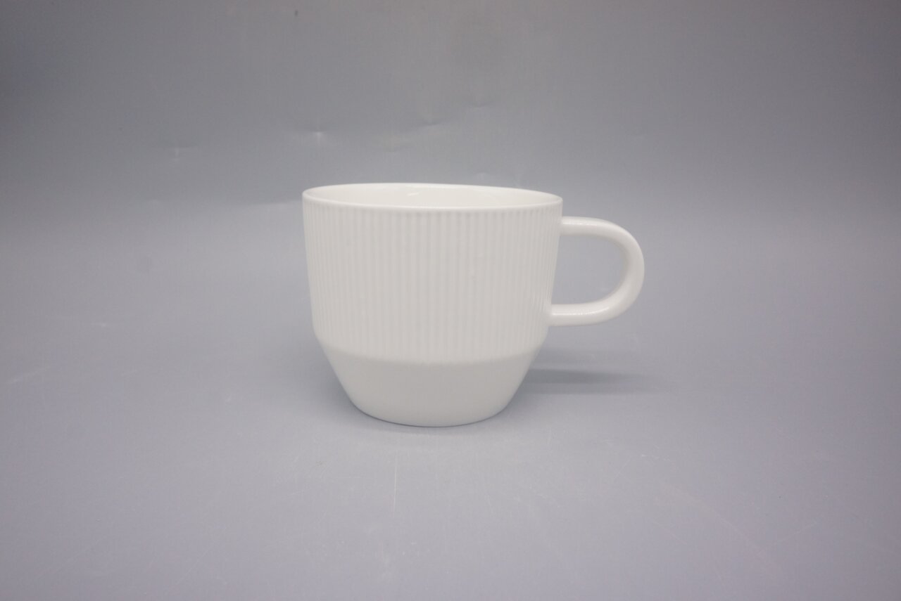Weiße Kaffeetasse mit geriffelter Oberfläche, seitliche Perspektive
