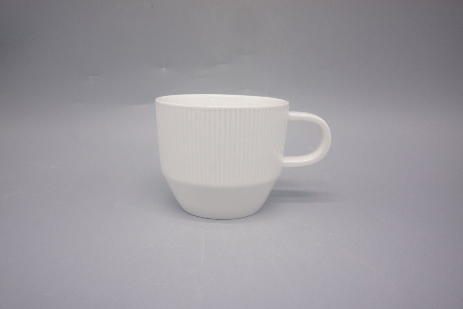 Weiße Kaffeetasse mit geriffelter Oberfläche, seitliche Perspektive