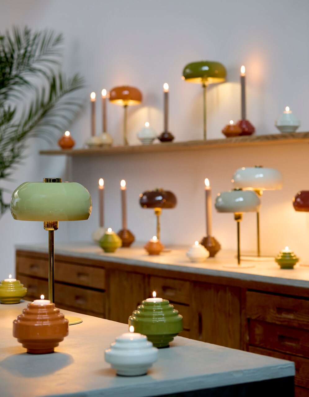 Tischleuchte SURIN in verschiedenen Farben auf einem Tisch, mit einer grünen Lampe im Vordergrund und mehreren Lampen im Hintergrund, seitliche Perspektive.