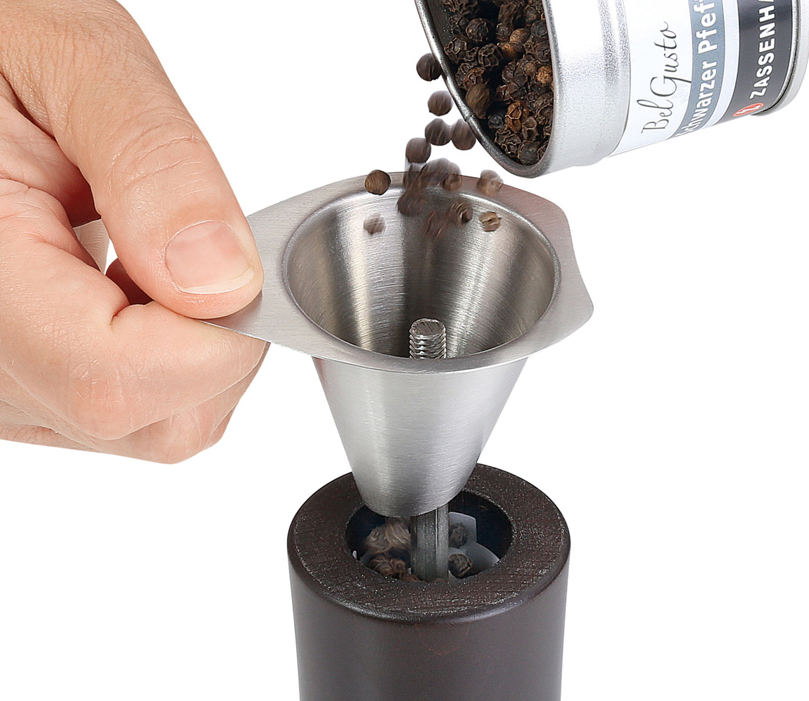 Einfülltrichter aus Edelstahl, der Pfefferkörner in eine Pfeffermühle füllt, aus der Perspektive von oben.