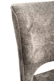 Nahaufnahme eines grauen, texturierten Stuhlrückens aus Stoff, seitliche Perspektive