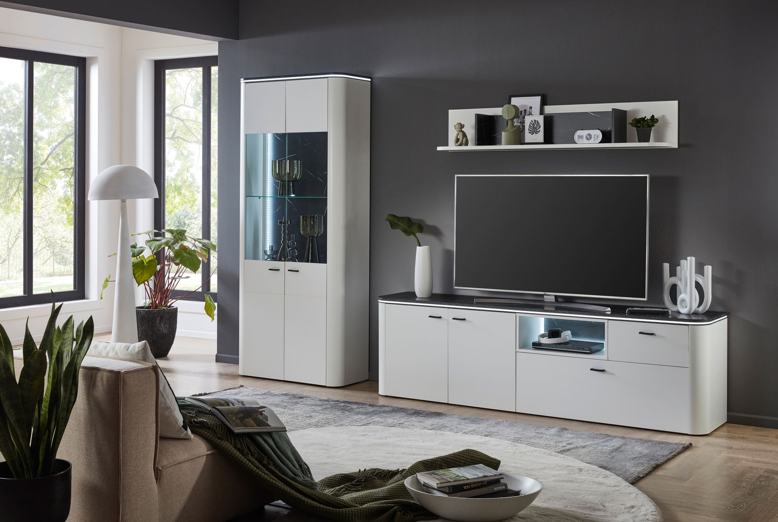 Zurbrüggen Wandcombinatie WAVE Moderne Wohnzimmer-Wandkombination in Weiß mit Vitrine, TV-Schrank und Regal, seitliche Perspektive.