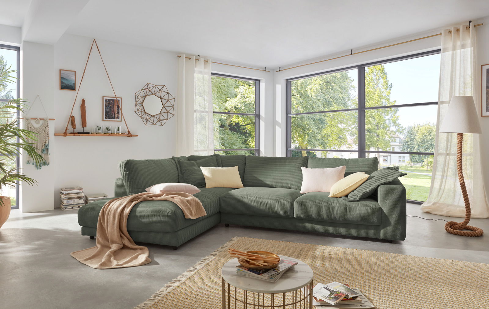 Lounge Handmade Ecksofa LH-SAMBIA Grüne Rundecke in einem modernen Wohnzimmer mit großen Fenstern, von vorne betrachtet.