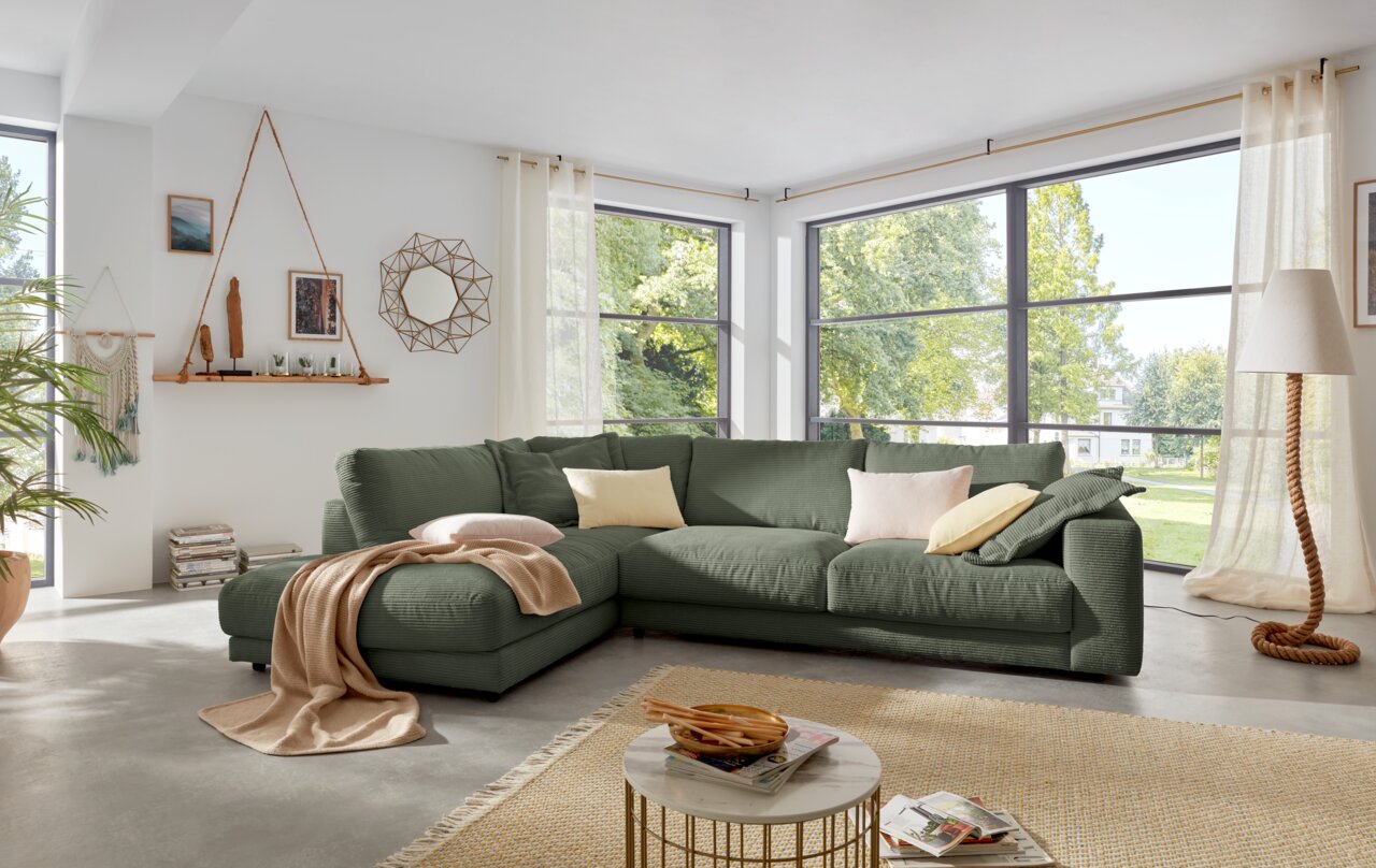 Lounge Handmade Ecksofa LH-SAMBIA Grüne Rundecke in einem modernen Wohnzimmer mit großen Fenstern, von vorne betrachtet.