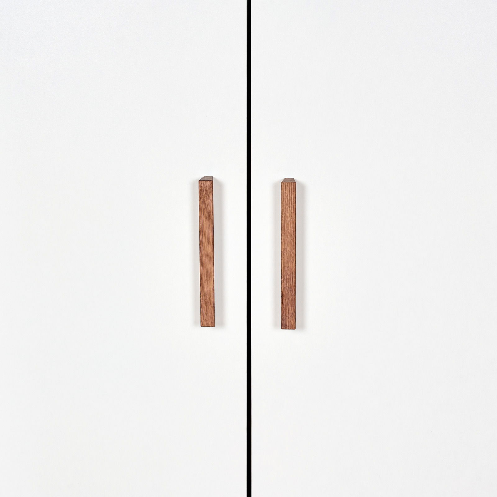 Vorderansicht eines weißen Kleiderschranks mit zwei Holztürgriffen.