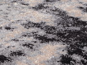 Nahaufnahme eines Designer-Teppichs mit abstraktem Muster in Schwarz, Grau und Beige.