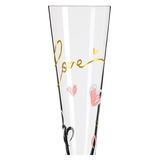 Nahaufnahme eines Champagnerglases mit goldener Schrift 'Love' und bunten Herzen.