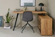 Hoekbureau van hout met een zwart metalen onderstel, grijze stoel met zwart onderstel, versierd met een lamp, planten en kantooraccessoires, vooraanzicht.