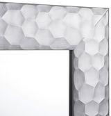 Nahaufnahme eines Spiegels mit facettiertem, geometrischem Rahmen in Silberoptik, Perspektive von der Ecke des Rahmens.