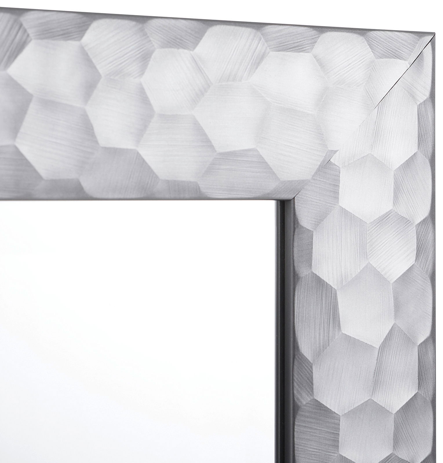 Nahaufnahme eines Spiegels mit facettiertem, geometrischem Rahmen in Silberoptik, Perspektive von der Ecke des Rahmens.
