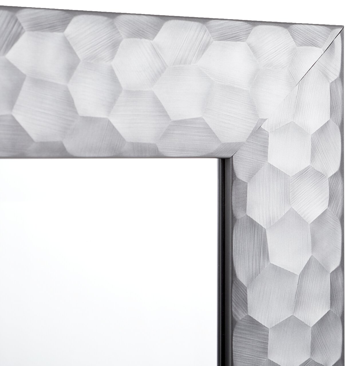 Nahaufnahme eines Spiegels mit facettiertem, geometrischem Rahmen in Silberoptik, Perspektive von der Ecke des Rahmens.