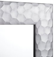 Nahaufnahme eines Spiegels mit facettiertem, geometrischem Rahmen in Silberoptik, Perspektive von der Ecke des Rahmens.