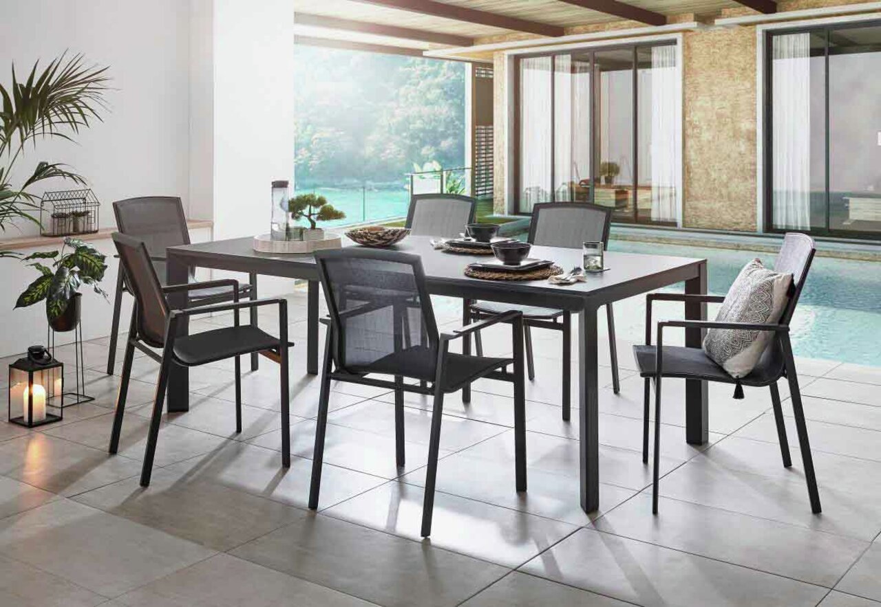 Amatio Stapelsessel HAMBURG Moderner Stapelsessel in einem eleganten Outdoor-Essbereich mit Blick auf den Pool, seitliche Perspektive.