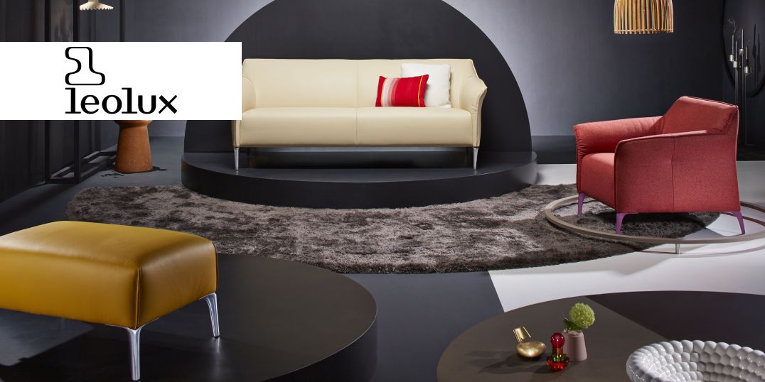 Modernes Wohnzimmer mit einem cremefarbenen Sofa, einem roten Sessel und einem gelben Hocker der Marke Leolux. 