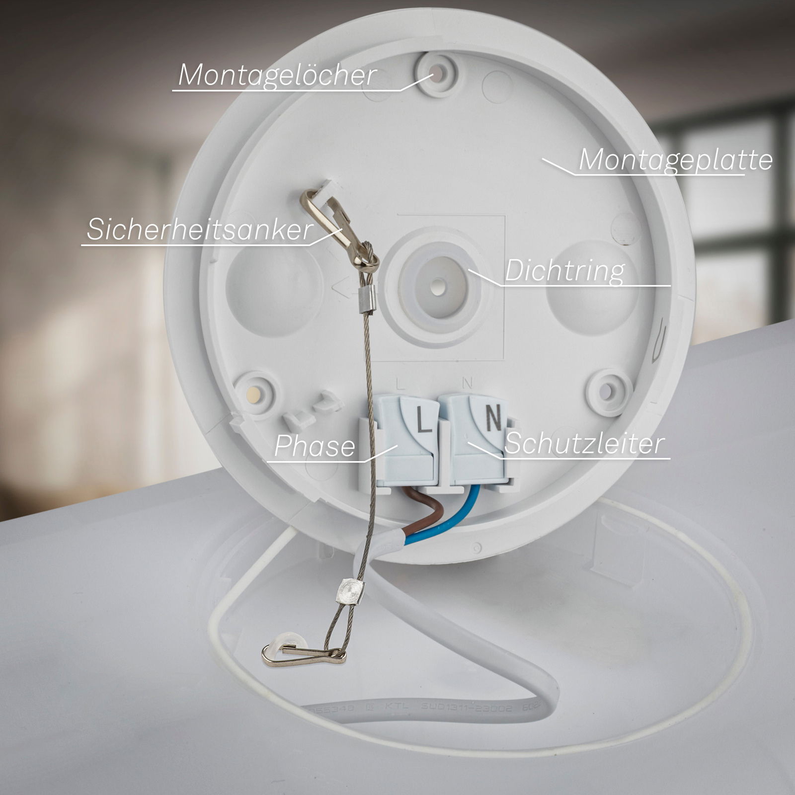 Rückansicht einer LED-Deckenleuchte mit Bewegungssensor, zeigt Montageplatte, Sicherheitsanker, Dichtungsring, Phasen- und Schutzleiteranschlüsse.