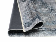 Teppich Vision Yama in Blau- und Grautönen, teilweise aufgerollt, zeigt detailliertes Muster aus der Seitenperspektive.