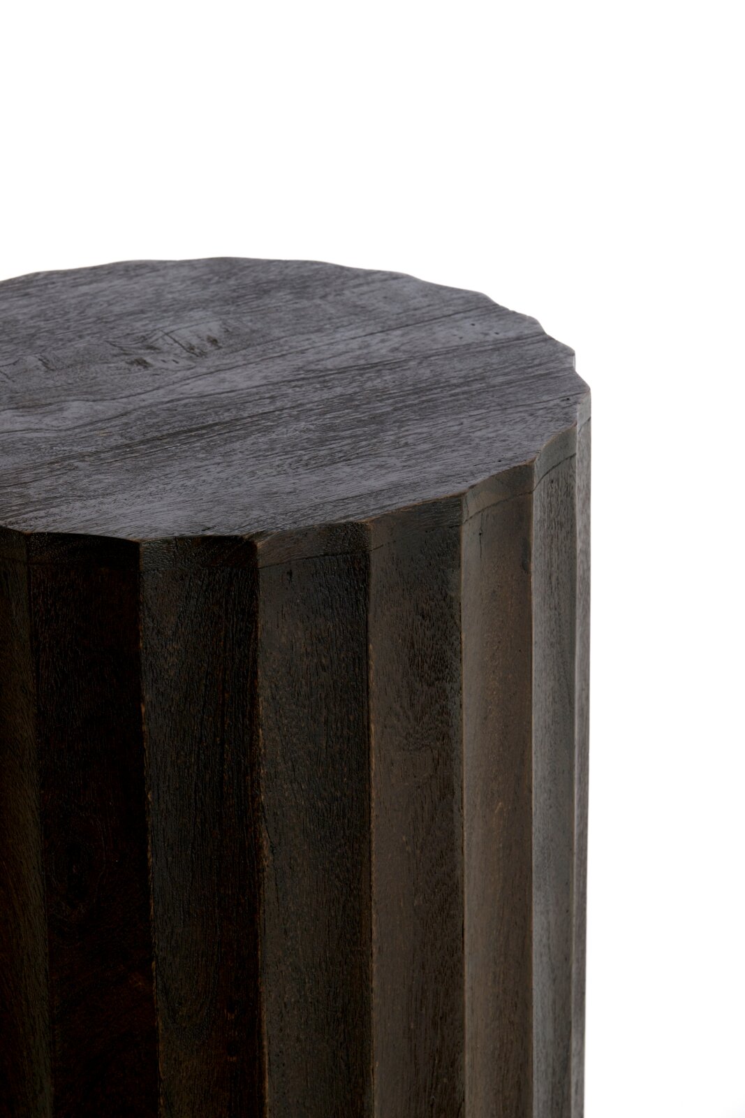 Nahaufnahme eines dunklen, facettierten Holzhockers oder Beistelltischs mit polygonaler Oberseite, schräg von oben aus der Ecke fotografiert (Draufsicht/3-4-Perspektive) vor weißem Hintergrund.