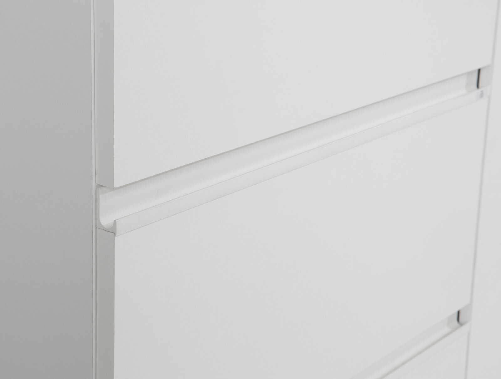 Nahaufnahme eines weißen Schwebetürenschranks mit klaren Linien und minimalistischen Griffen, seitliche Perspektive.