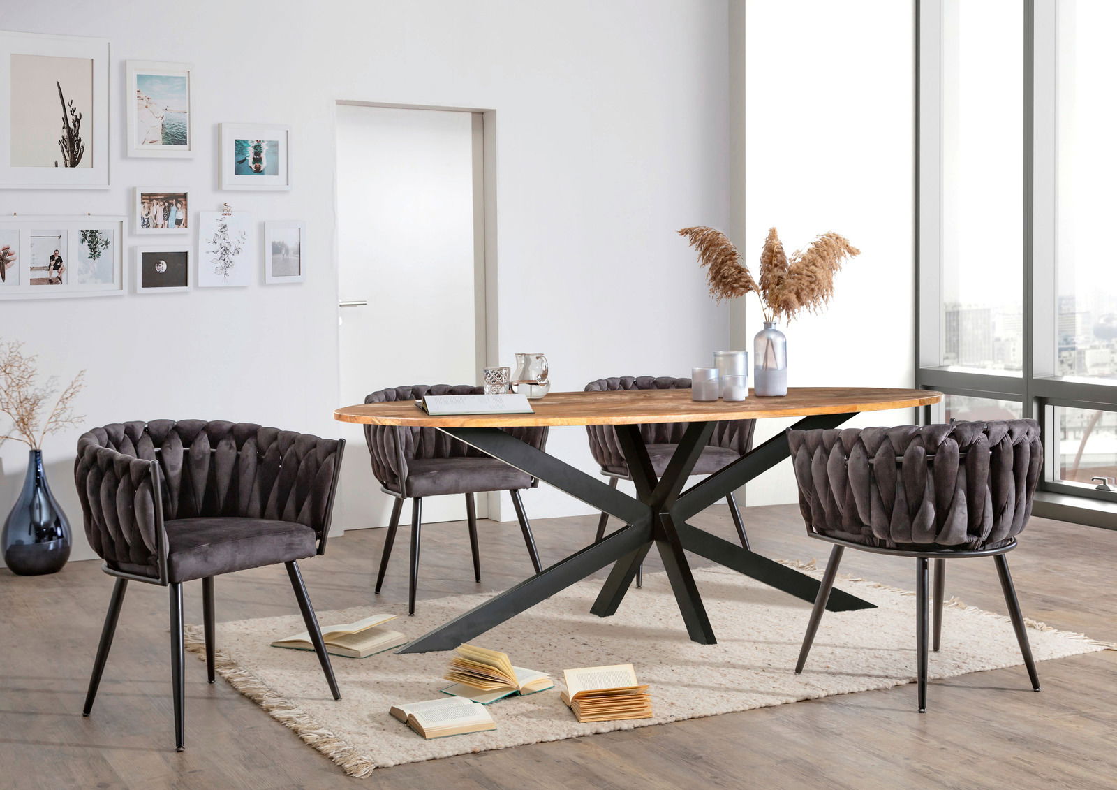 Moderner Esstisch mit Holzplatte und schwarzem Metallgestell, umgeben von vier gepolsterten Stühlen in einem hellen Raum mit großen Fenstern, seitliche Perspektive.