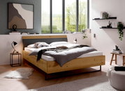 Modern houten futonbed in een stijlvolle slaapkamer met grote ramen, zijaanzicht.
