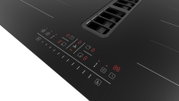 Schwarzes Induktionskochfeld mit integriertem Dunstabzug, Touch-Bedienfeld und roten LED-Anzeigen, schräg von oben aus der Nahaufnahme fotografiert.
