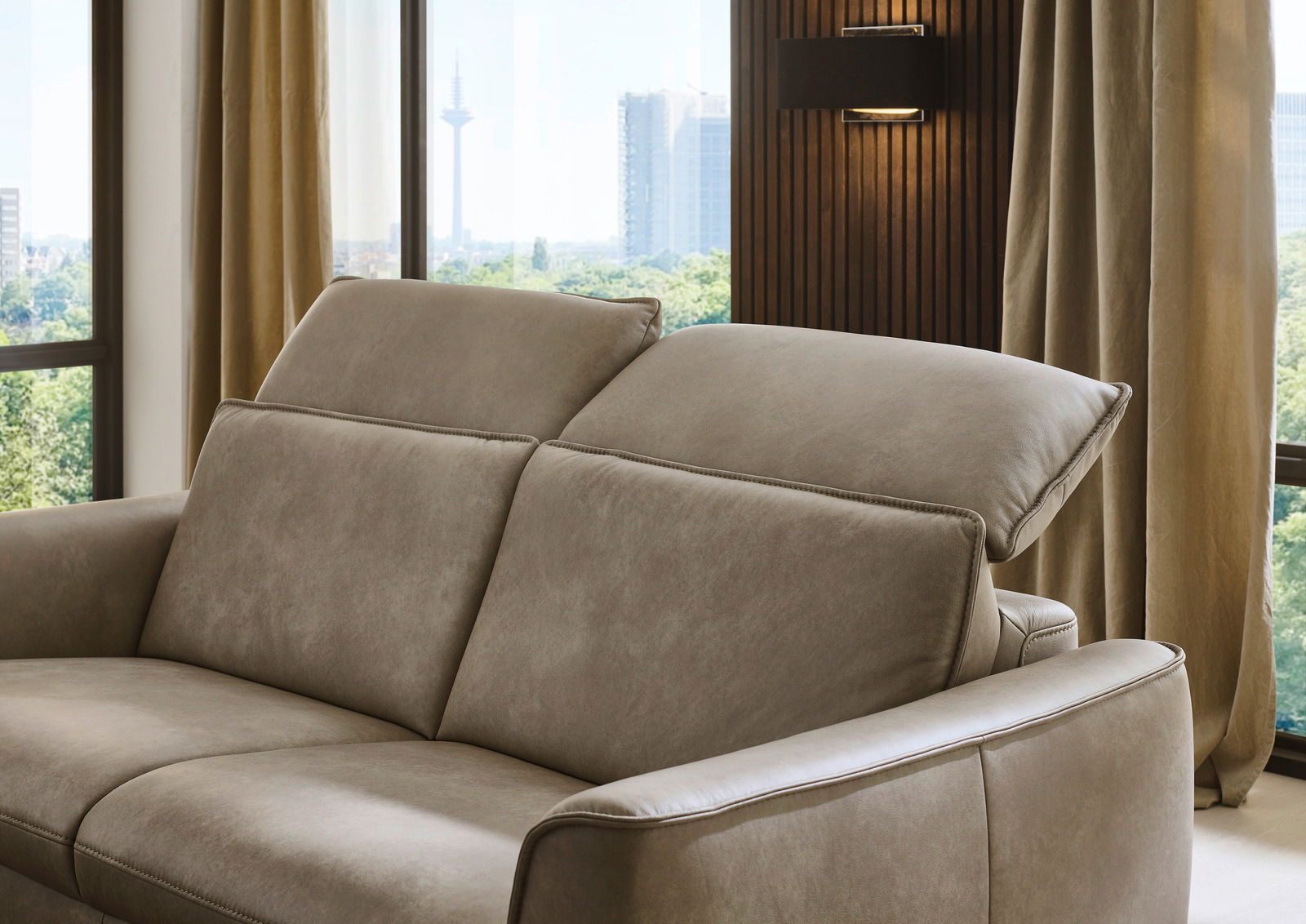 Beiges Sofa mit verstellbaren Kopfstützen, seitliche Perspektive, modernes Wohnzimmerambiente.