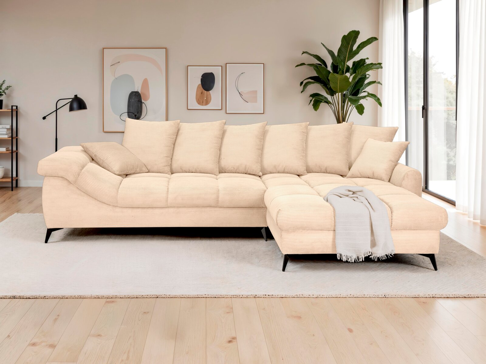 Beiges, großformatiges Cord-Ecksofa mit rechter Ottomane/Longchair, vielen Rückenkissen und schwarzen Metallfüßen im modernen Wohnzimmer, frontale Ansicht