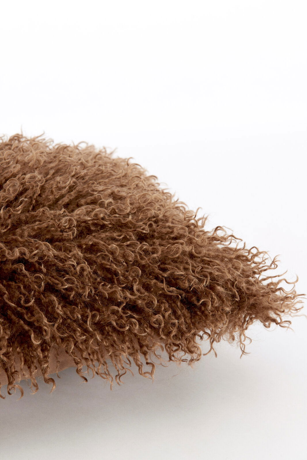 Nahaufnahme eines braunen, flauschigen Kissens mit lockiger Textur.