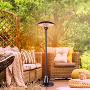 Standheizstrahler auf einer Terrasse mit gemütlichen Rattanmöbeln, aus der Perspektive von vorne aufgenommen.