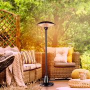 Standheizstrahler auf einer Terrasse mit gemütlichen Rattanmöbeln, aus der Perspektive von vorne aufgenommen.