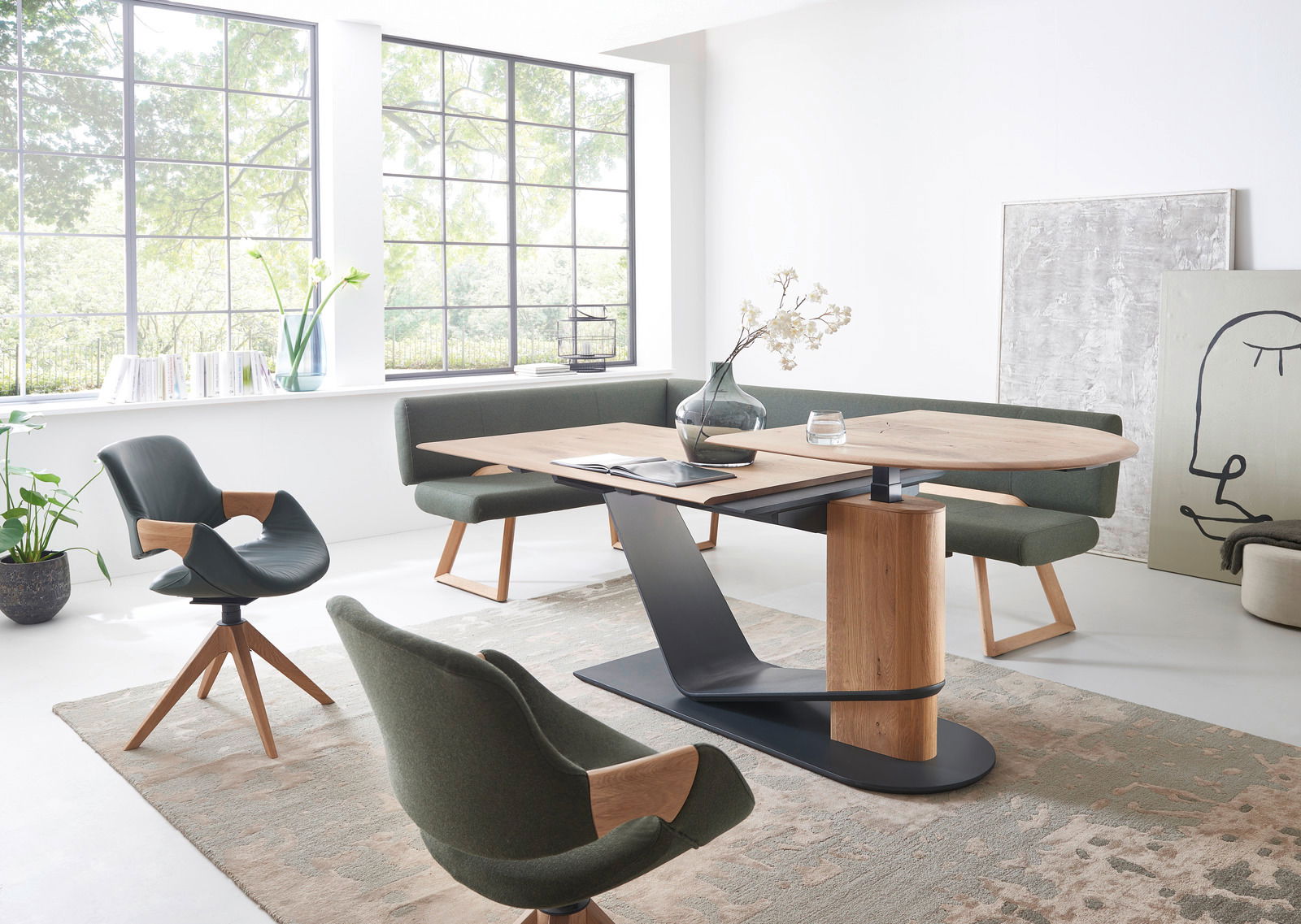 Moderner Essbereich mit einem Esstisch aus Holz und Metall, umgeben von grünen Stühlen und einer Eckbank, seitliche Perspektive.