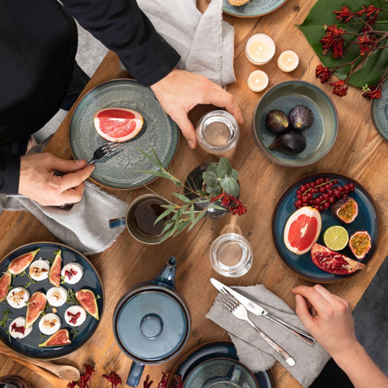 Like by Villeroy & Boch Frühstücks-Set 6-tlg CRAFTED BREEZE Vogelperspektive auf ein stilvoll gedecktes Frühstücks-Set mit blauem Geschirr, frischen Früchten und Kerzen auf einem Holztisch.