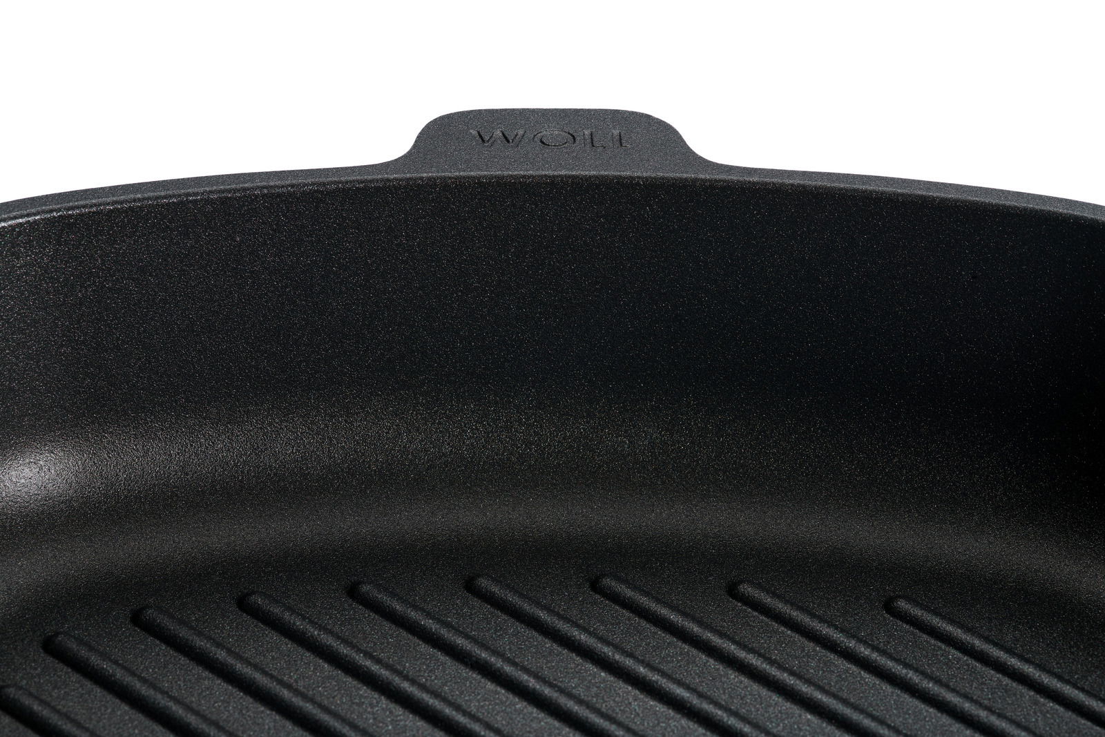 Nahaufnahme einer schwarzen Guss-Steakpfanne mit geriffeltem Boden, Marke Woll, von oben betrachtet.