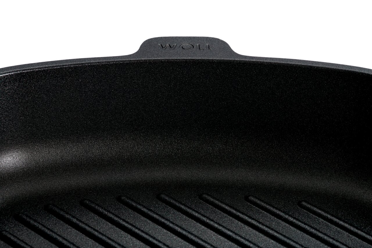 Nahaufnahme einer schwarzen Guss-Steakpfanne mit geriffeltem Boden, Marke Woll, von oben betrachtet.