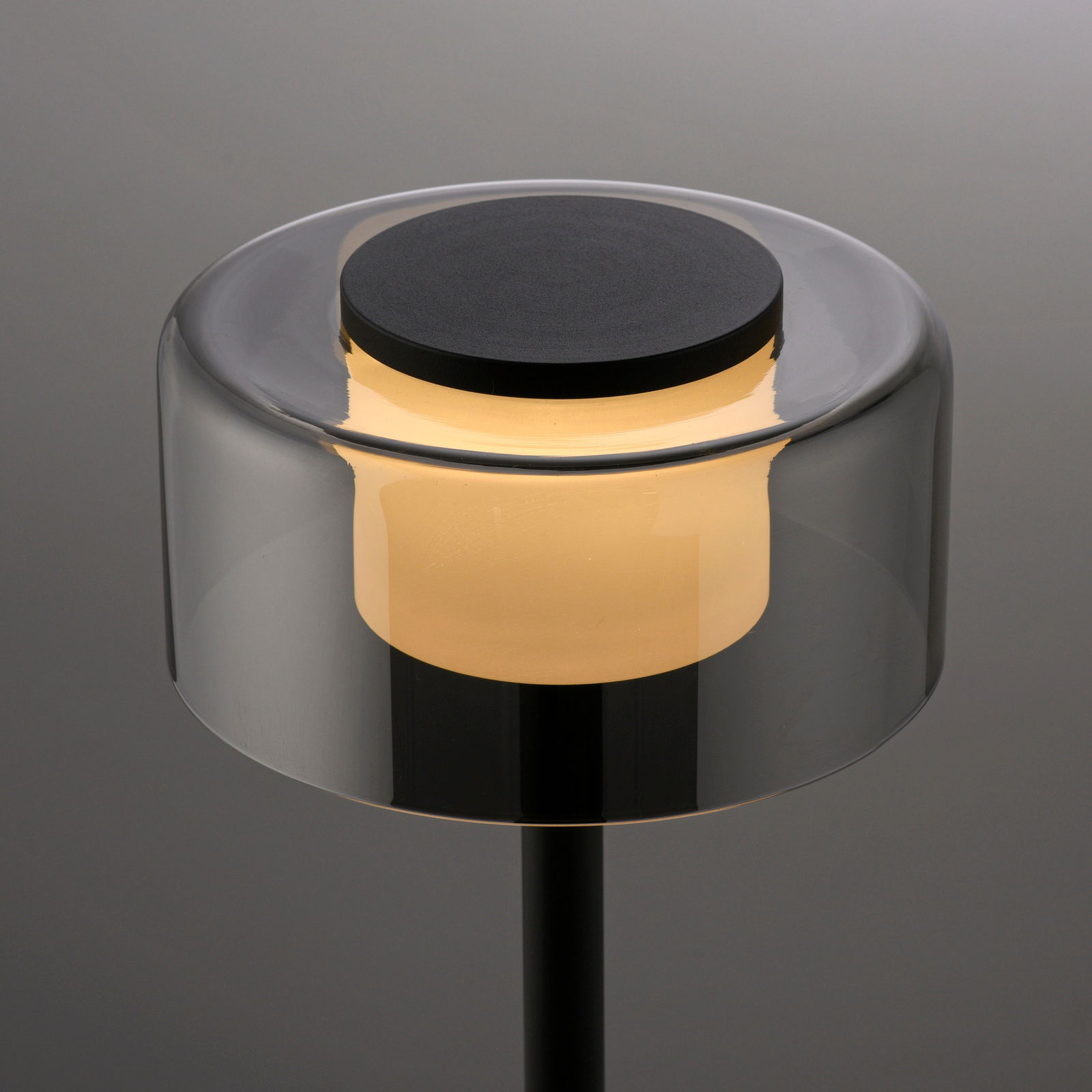 Moderne Tischleuchte RIKA mit zylindrischem, transparentem Schirm und warmem Licht, seitliche Perspektive