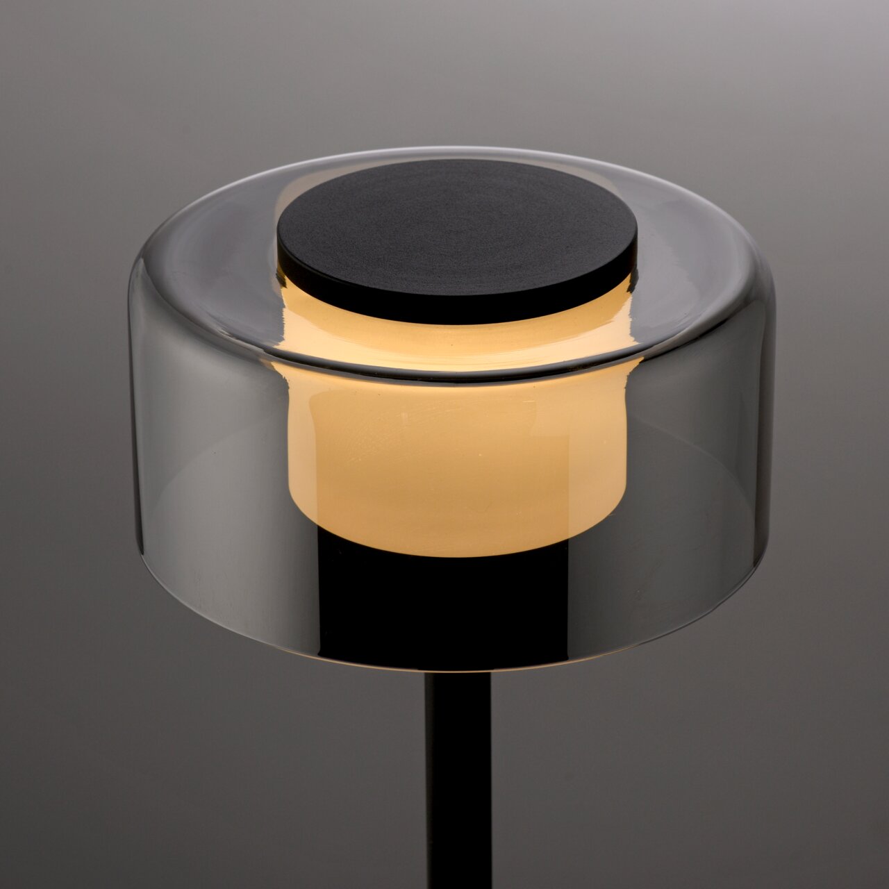 Moderne Tischleuchte RIKA mit zylindrischem, transparentem Schirm und warmem Licht, seitliche Perspektive