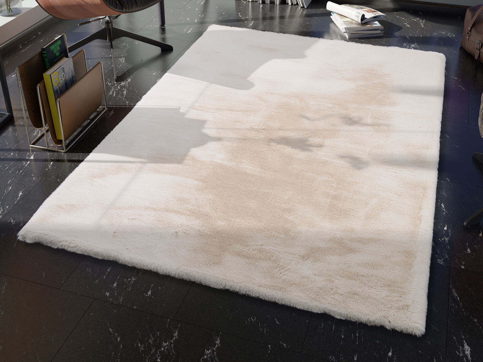OCI Fellteppich ROCKY SOFT Ein weicher, beiger Fellteppich liegt auf einem dunklen Marmorboden in einem modernen Raum. Die Perspektive zeigt den Teppich von schräg oben, mit einem Stuhl und einem Zeitschriftenhalter im Hintergrund.
