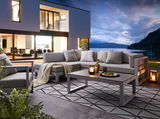 Modernes Lounge-Set auf einer Terrasse mit Blick auf einen See bei Sonnenuntergang, seitliche Perspektive.
