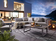 Modernes Lounge-Set auf einer Terrasse mit Blick auf einen See bei Sonnenuntergang, seitliche Perspektive.