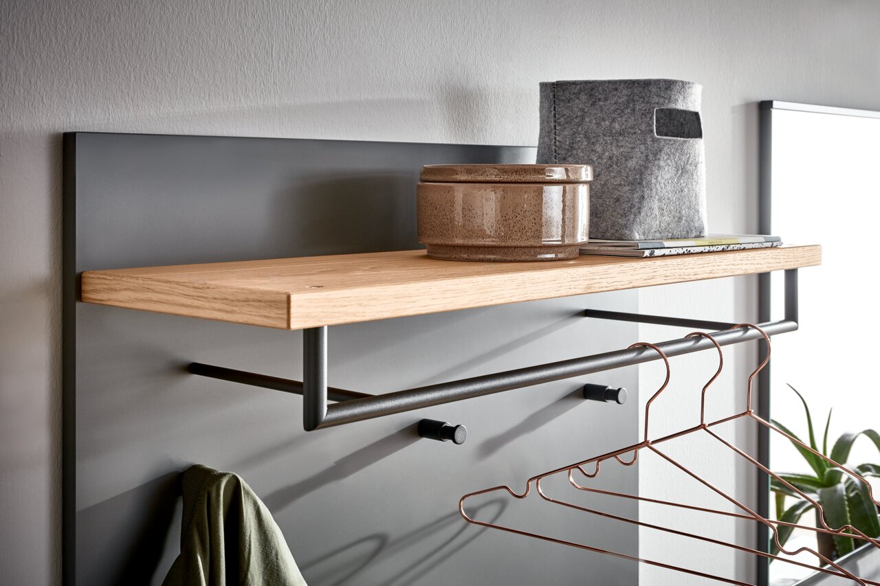 Nahaufnahme eines modernen Garderoben-Sets mit Holzablage, Kleiderstange und Haken, seitliche Perspektive.