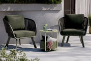 Moderner Beistelltisch in hellgrünem Design, umgeben von zwei stilvollen Sesseln auf einer Terrasse, seitliche Perspektive.