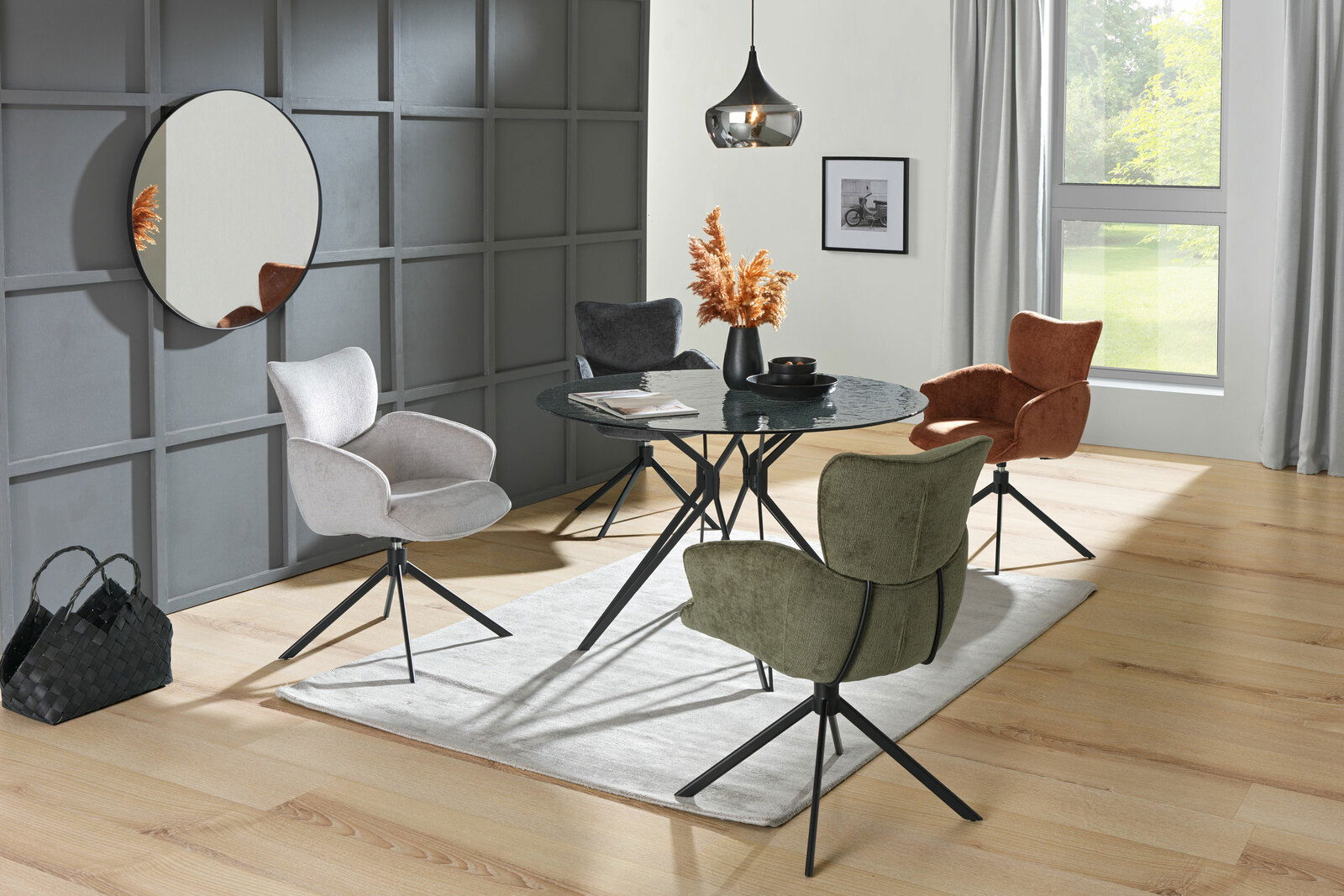 Moderner Esstisch mit rundem, dunklem Glas und schwarzen Metallbeinen, umgeben von vier farblich unterschiedlichen Stühlen in einem stilvollen Esszimmer. Perspektive: seitlich.