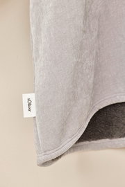 Nahaufnahme eines grauen Lounge Hoodies mit weichem Innenfutter und sichtbarem Markenetikett, seitliche Perspektive.