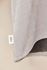 Nahaufnahme eines grauen Lounge Hoodies mit weichem Innenfutter und sichtbarem Markenetikett, seitliche Perspektive.